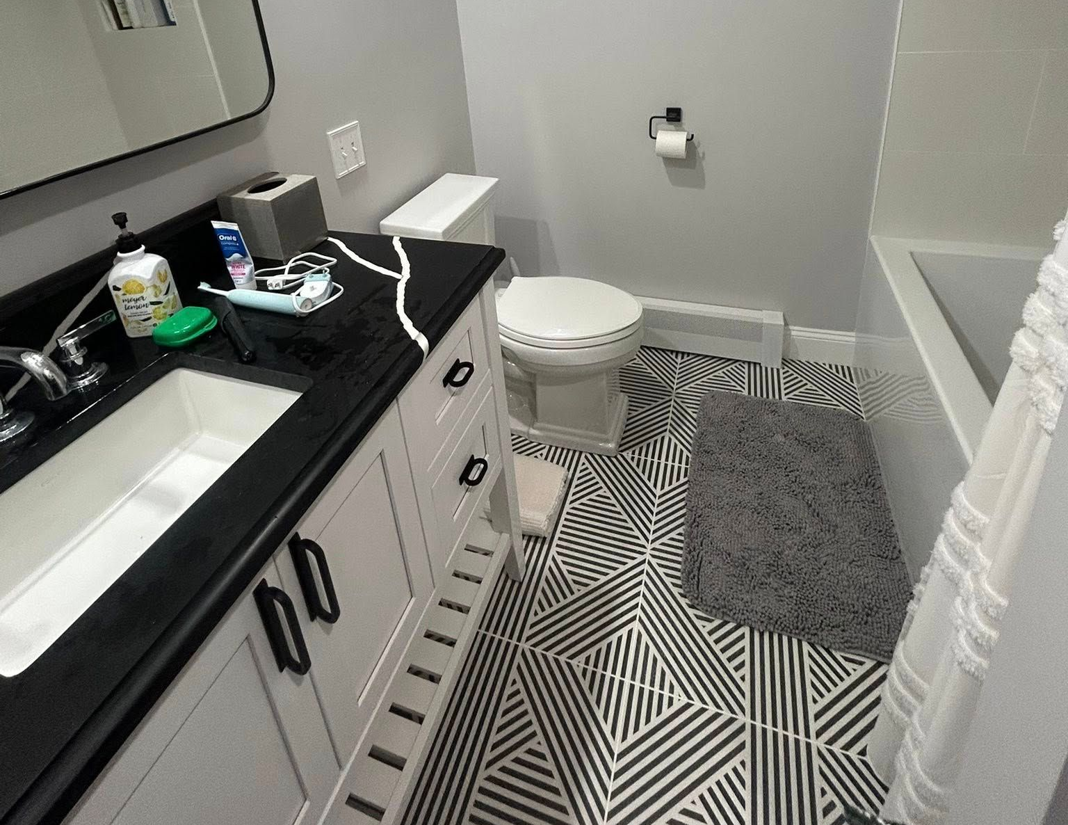 Modern gray and white bathroom with a bathtub, shower, toilet, and shelves. Modern gray and white bathroom with a bathtub, shower, toilet, and shelves.