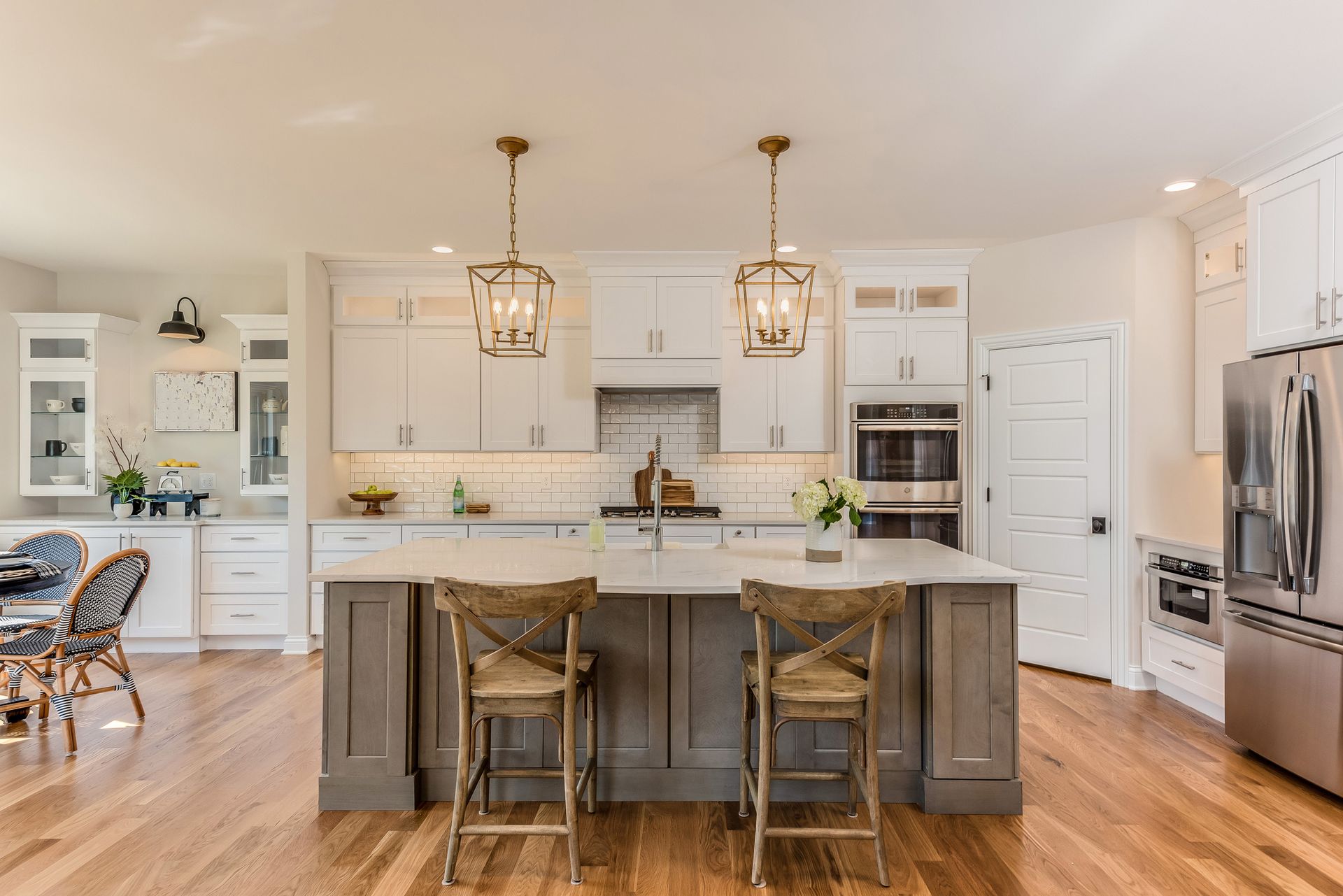 Modern kitchen with island, wood floors, white and gray cabinets, two pendant lights.