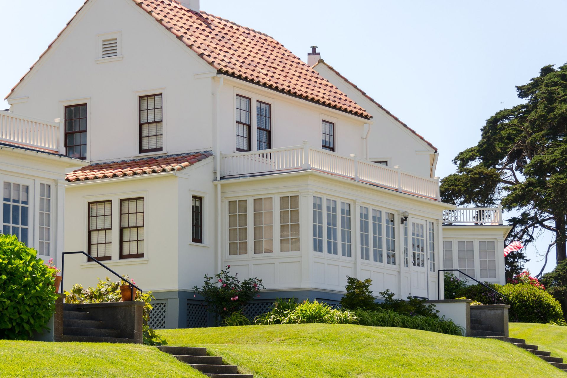 White house with orange tile roof, surrounded by green grass and trees on a sunny day. White house with orange tile roof, surrounded by green grass and trees on a sunny day.