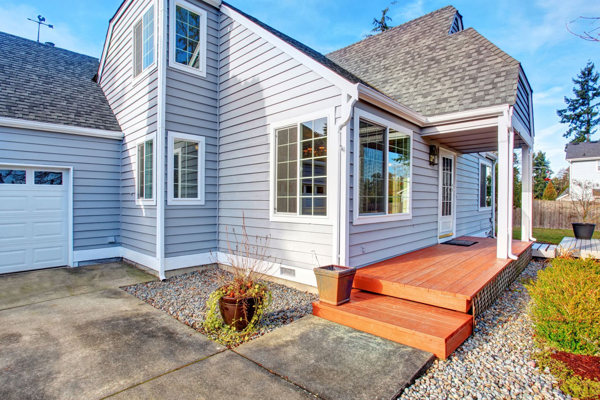 Two-story house with light blue siding, gray roof, and orange deck and stairs. Two-story house with light blue siding, gray roof, and orange deck and stairs.