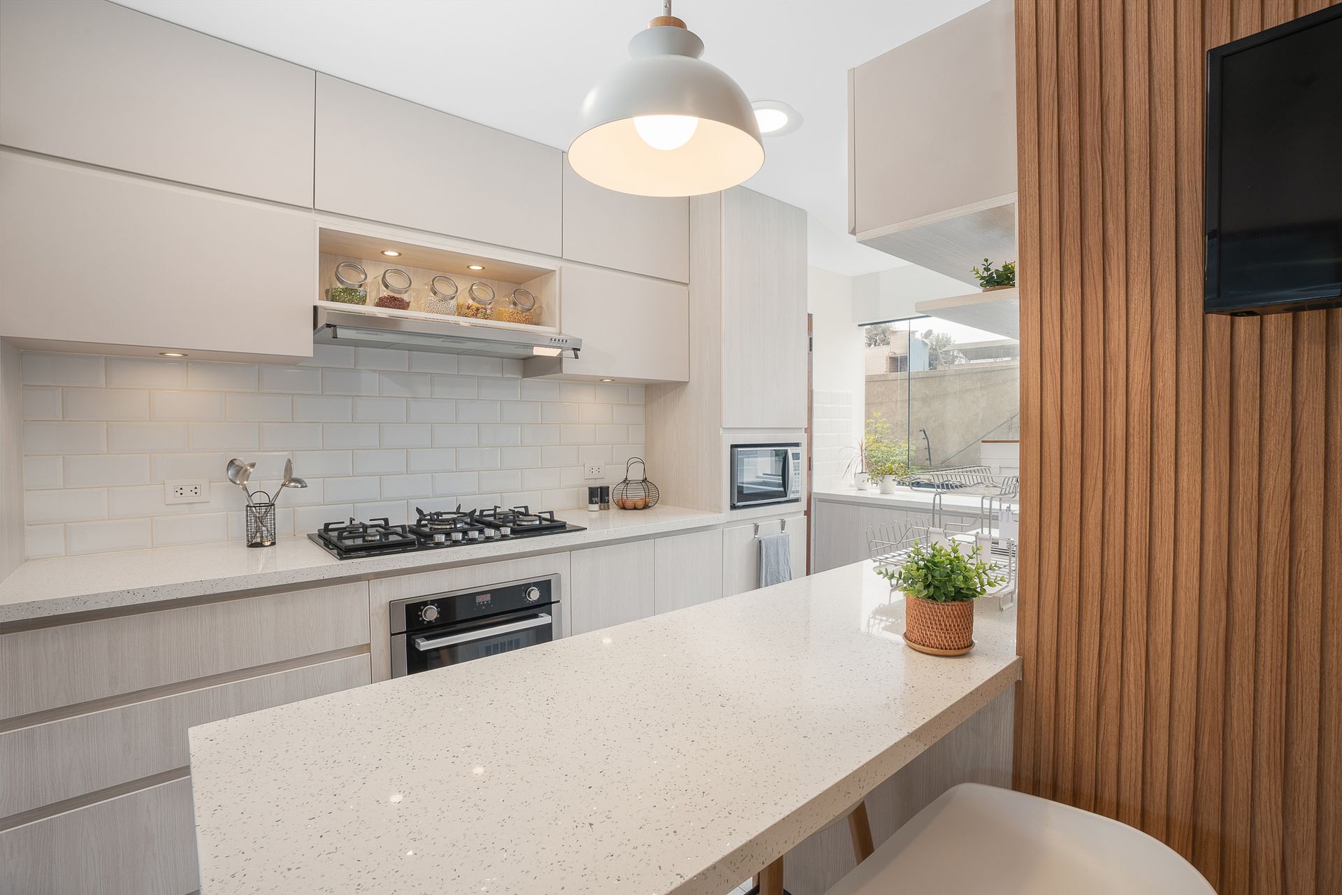 Modern kitchen with white cabinets, countertops, and subway tile backsplash. Includes gas stovetop, oven, and microwave.