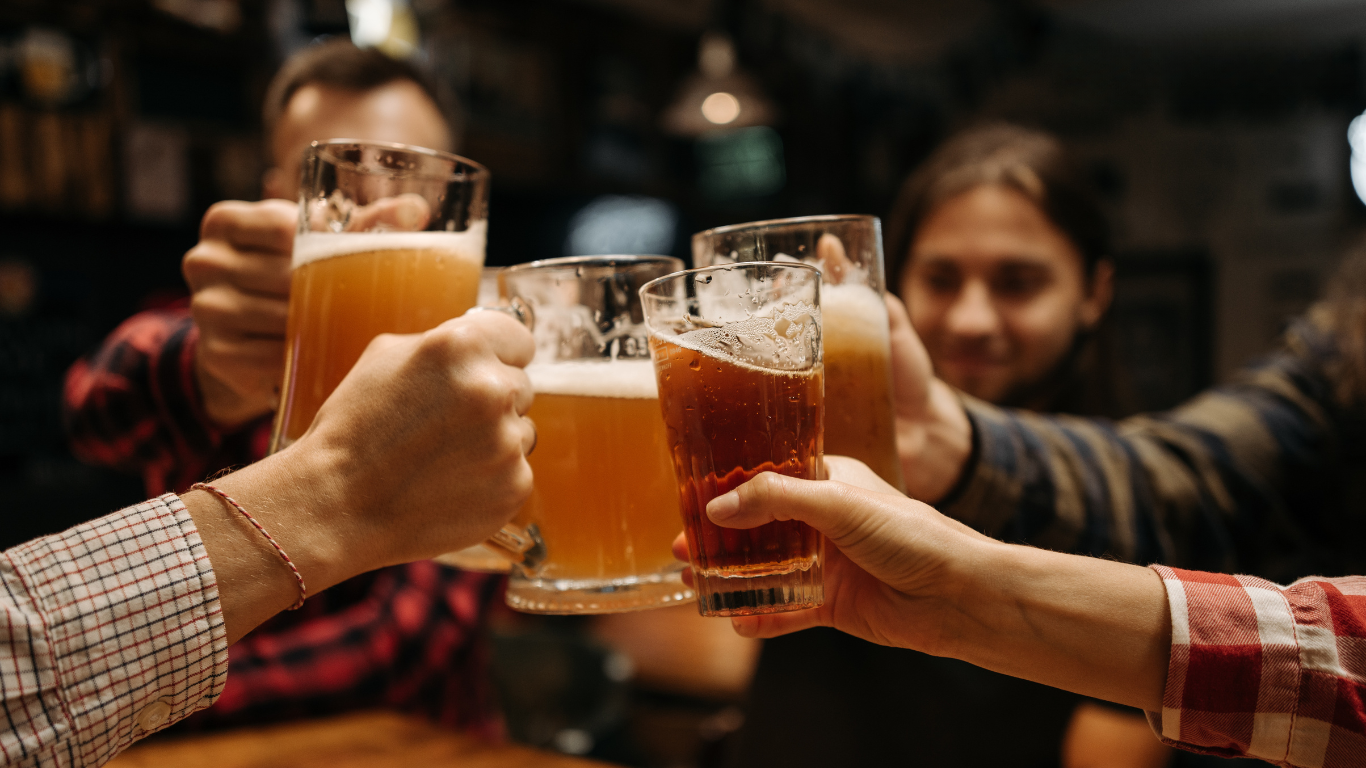 A group of people are toasting with beer mugs in a bar.