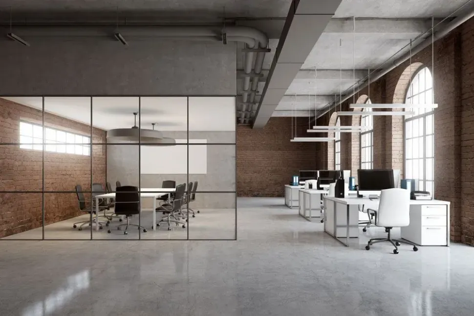 An empty office with a conference room and a brick wall.