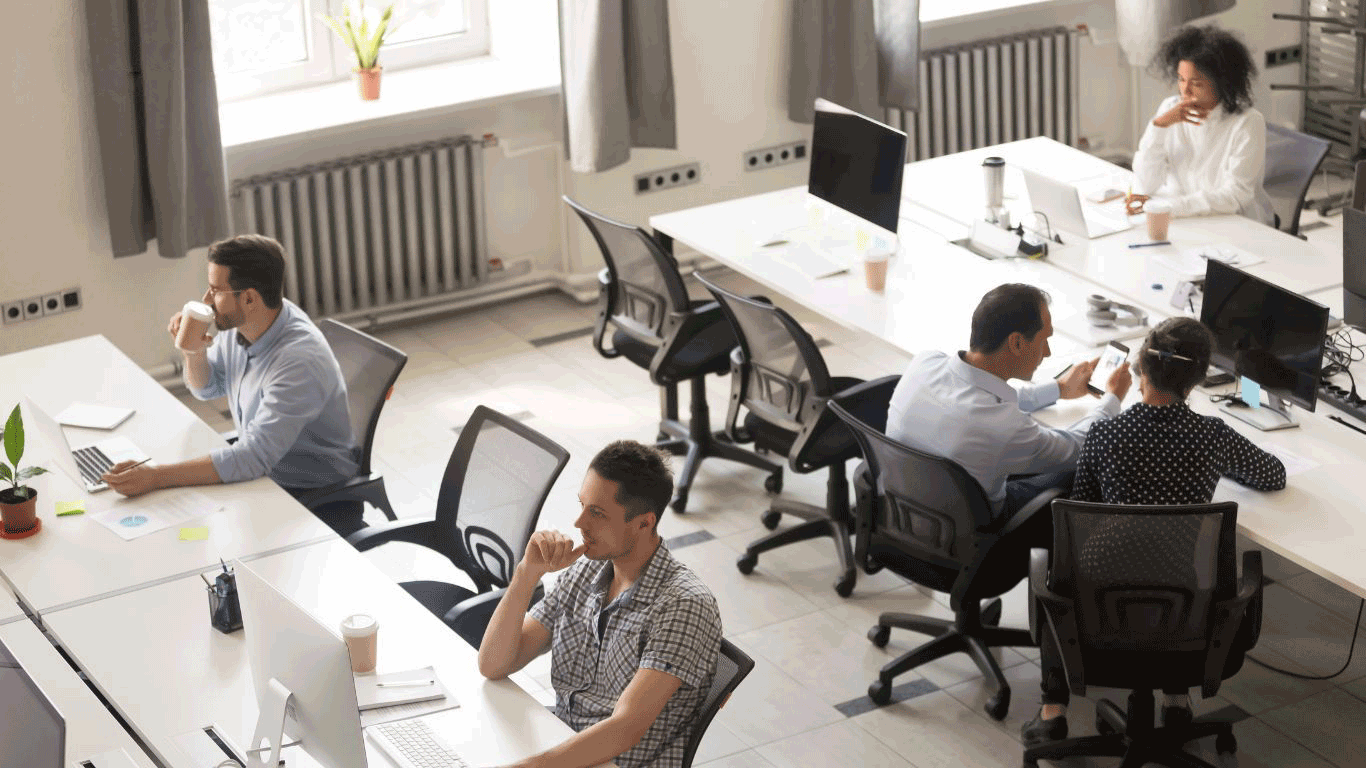 A group of people are sitting at desks in an office.