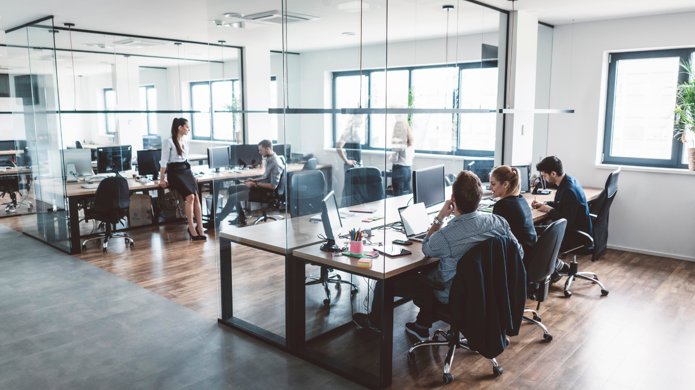 A group of people are sitting at desks in an office.