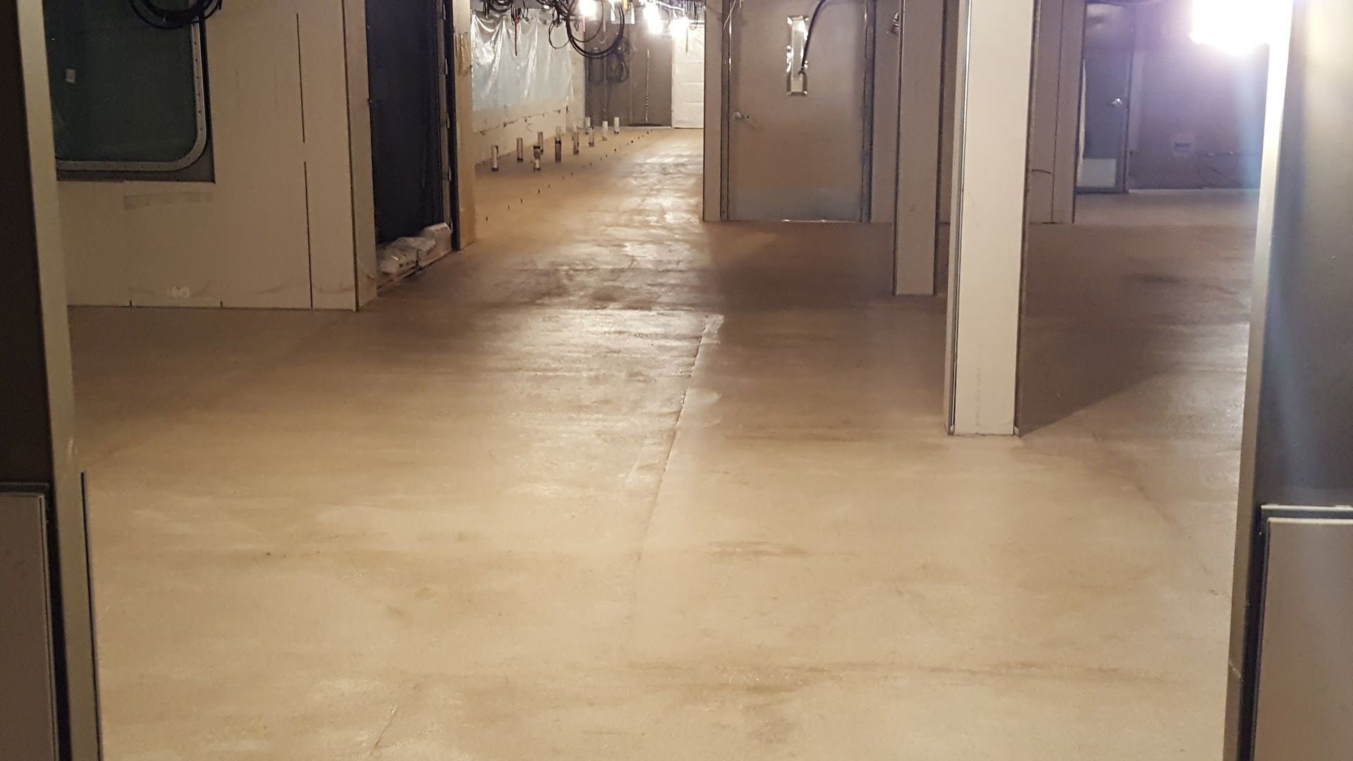 Basement with light-colored wooden floors. Walls show signs of renovation. Several doorways lead further into the space.