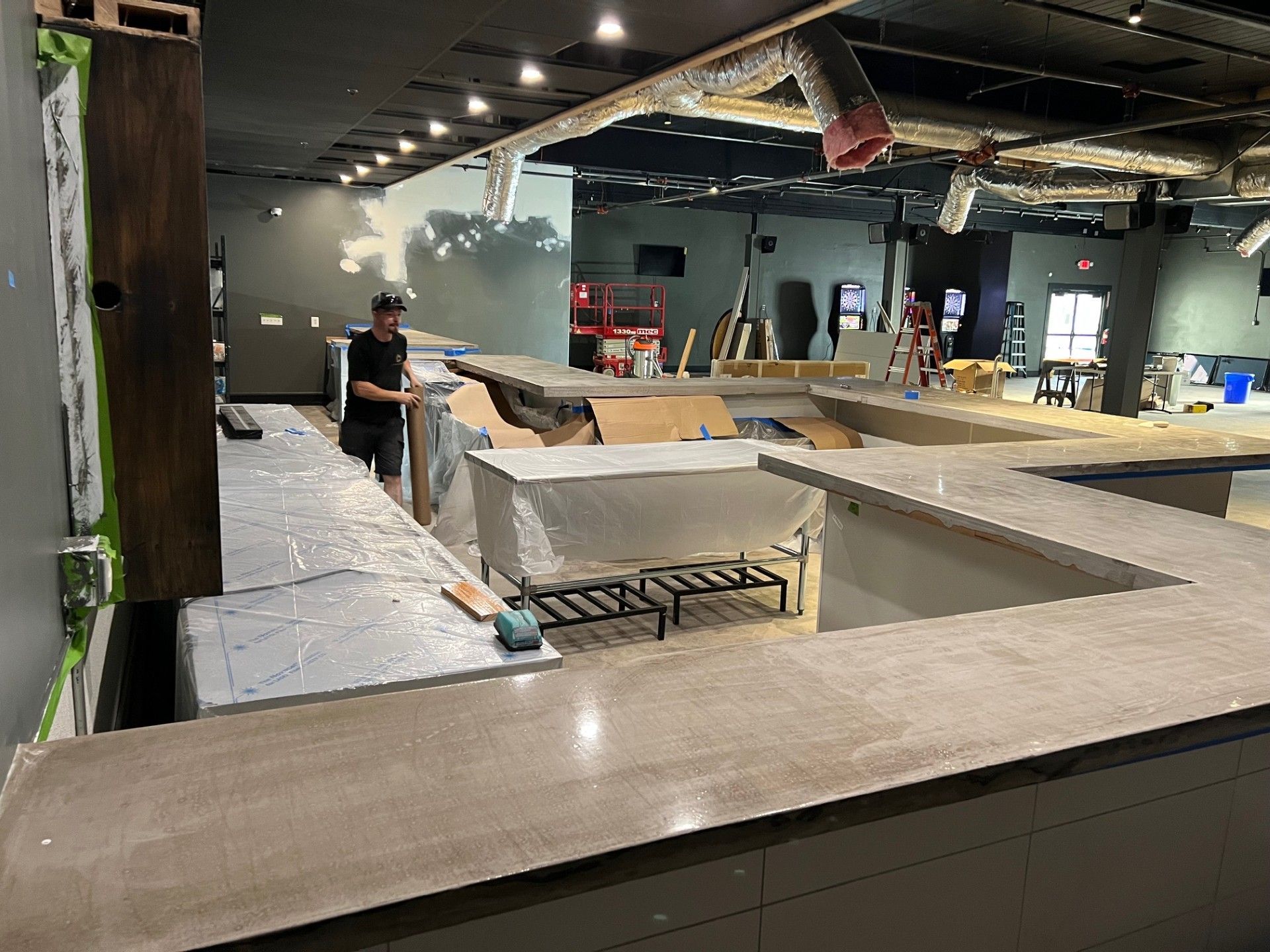 A bar under construction, with a worker, countertops, and a partially finished interior.