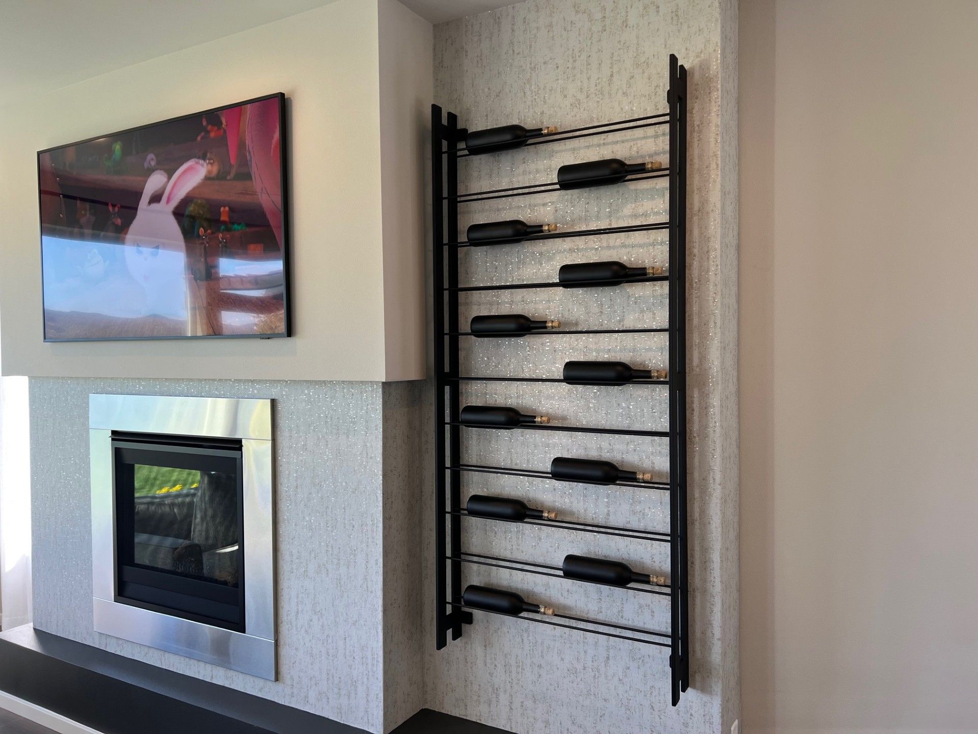 Wine rack with bottles next to a fireplace and a painting on the wall.