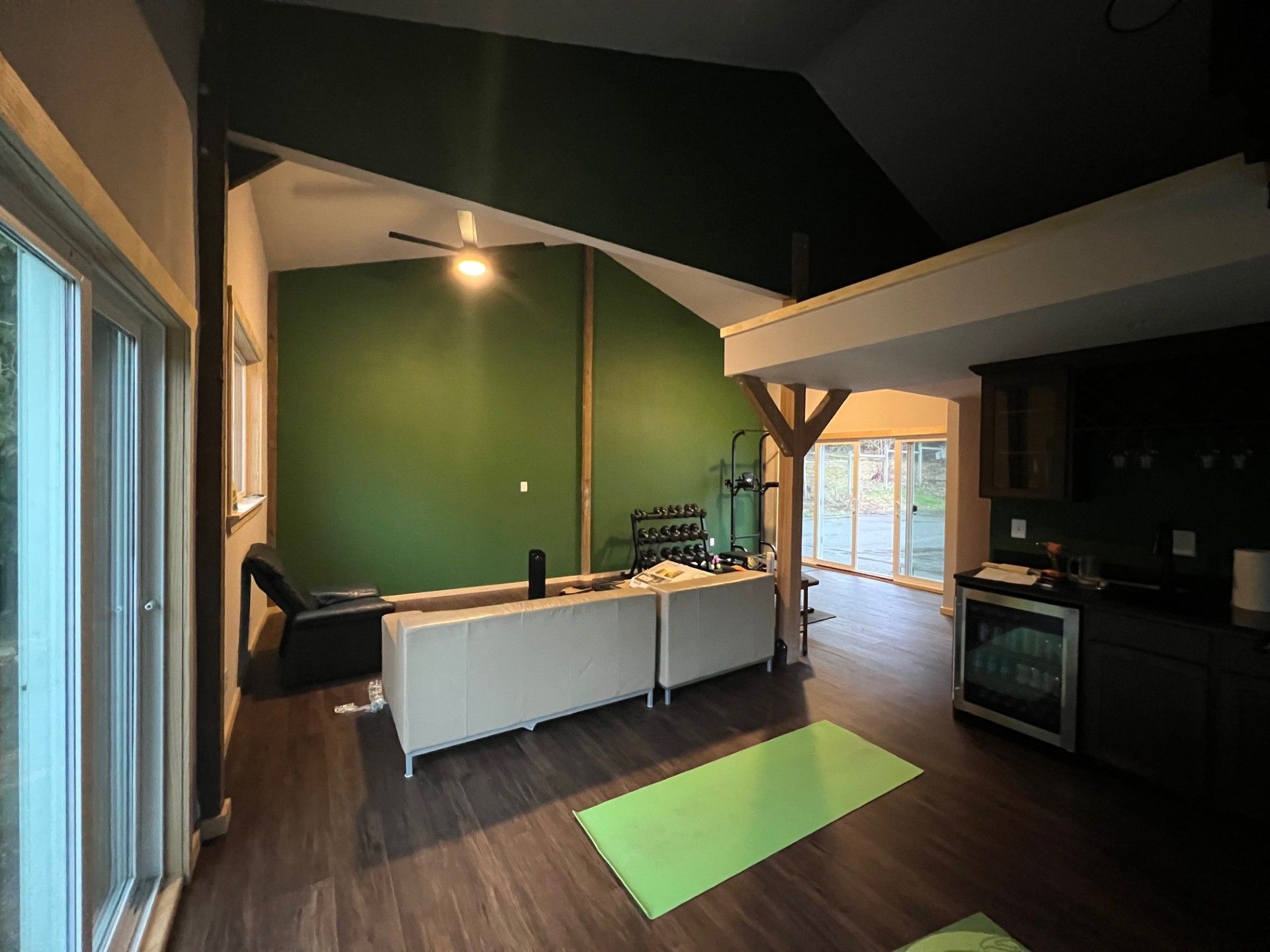 Interior of a room with a green accent wall, wood floor, and white furniture.
