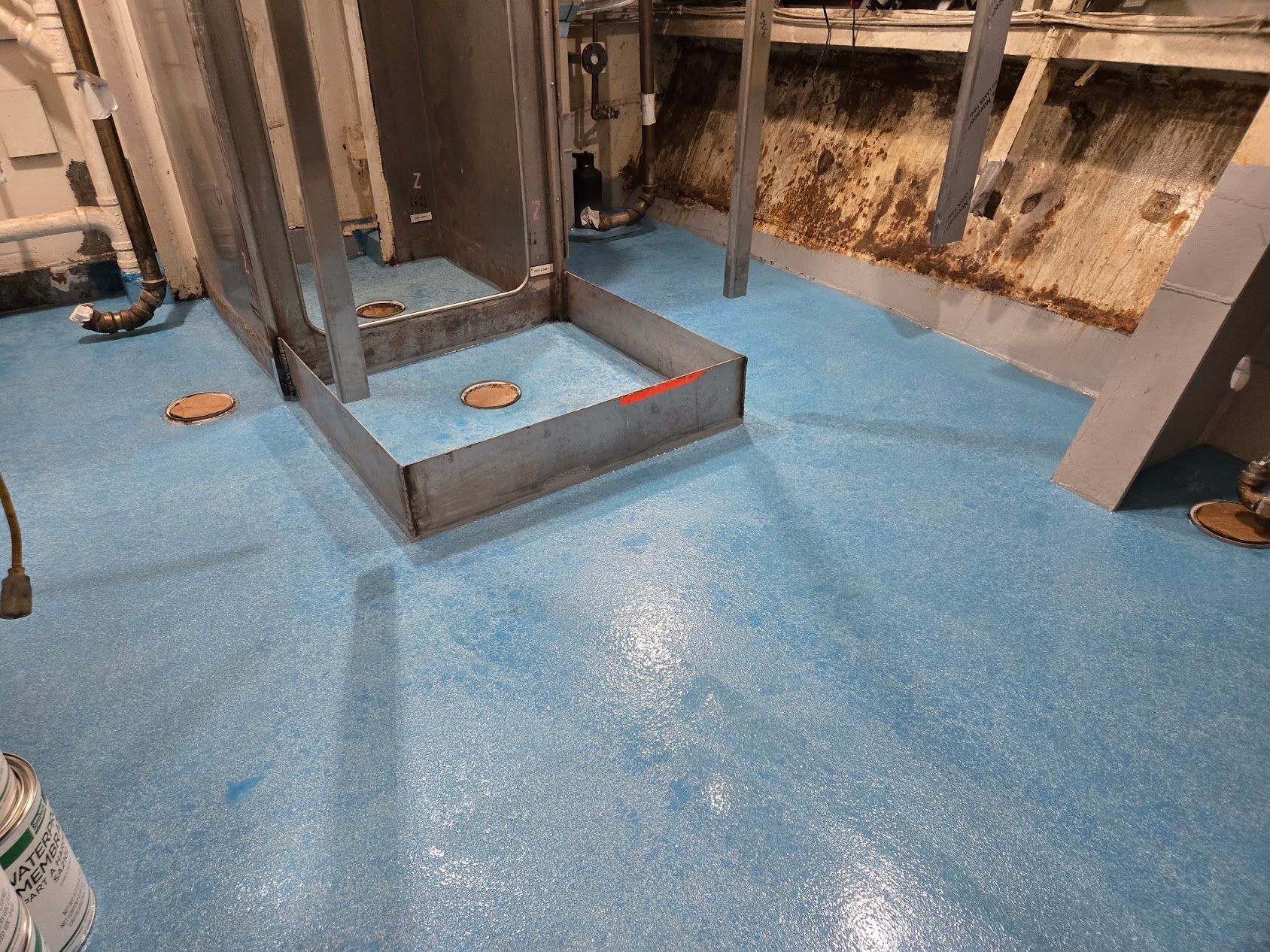 Blue speckled industrial floor with metal fixtures; a light-colored room.