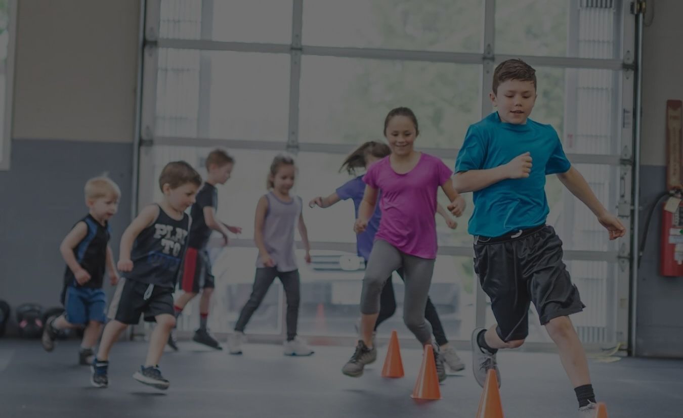 Un groupe d'enfants court autour de cônes dans un gymnase.