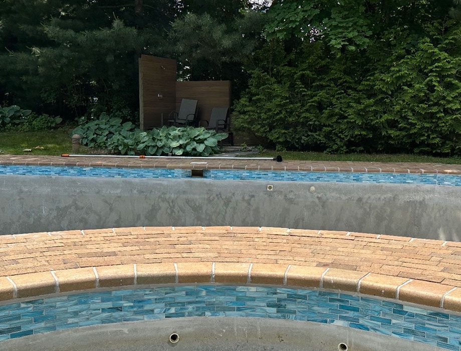 a swimming pool with a brick border and blue tiles