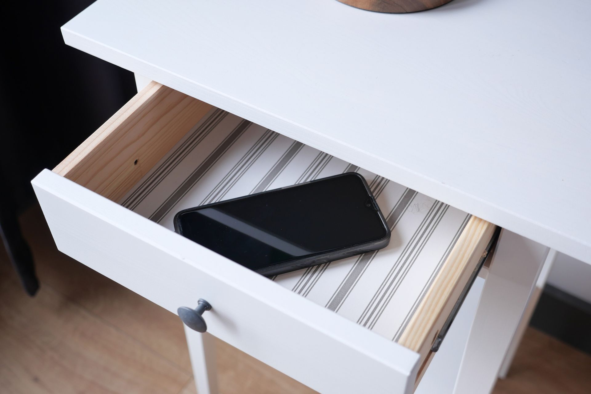 A cell phone is sitting in the drawer of a white nightstand.| Kansas City, KS | APA A cell phone is sitting in the drawer of a white nightstand.| Kansas City, KS | APA