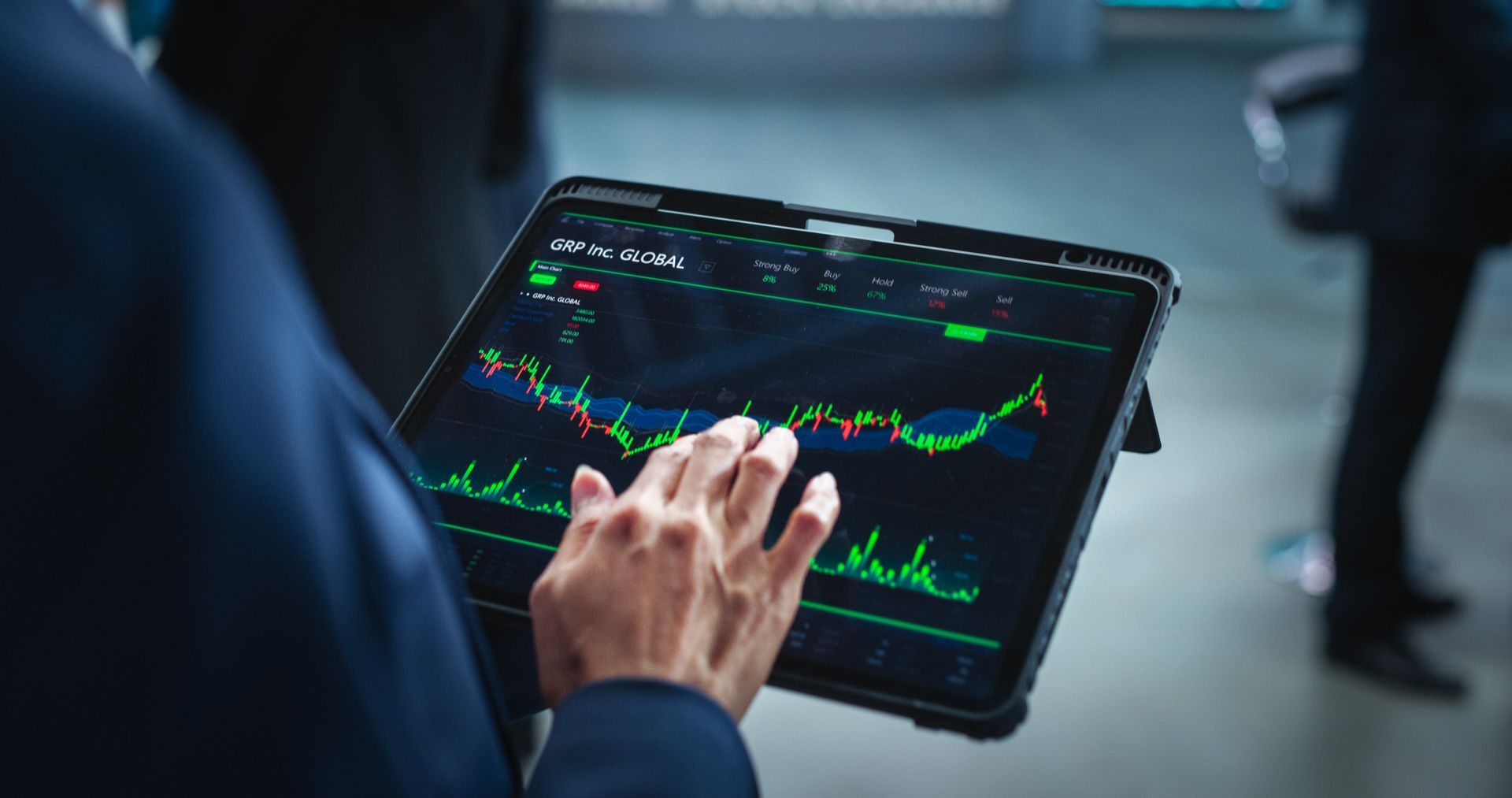 Person in blue suit, analyzing stock market data on a tablet. Green and white financial chart displayed.