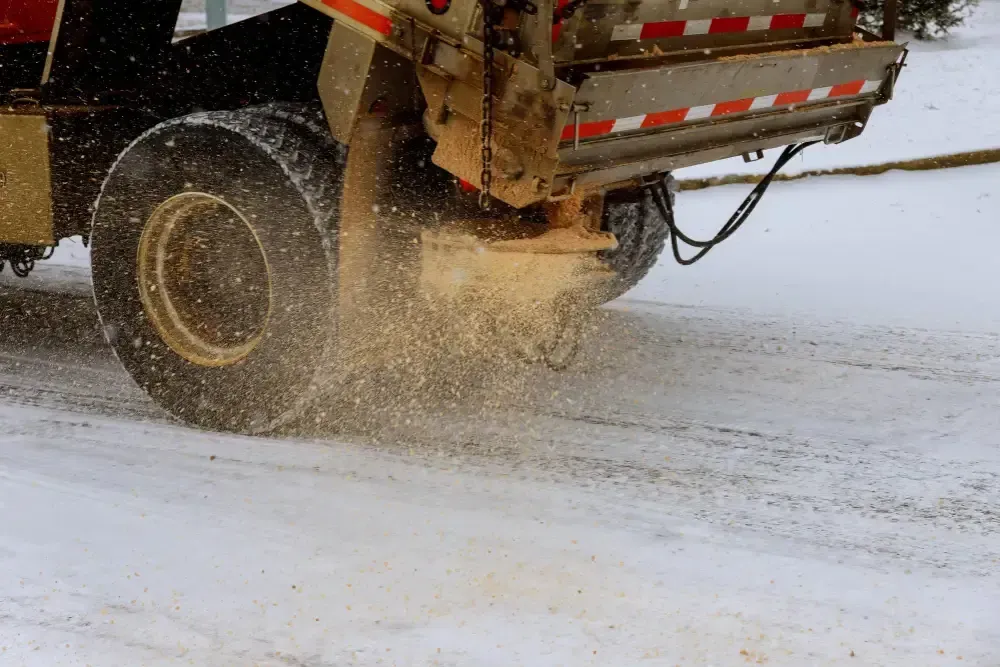 Een zoutwagen strooit zout op een met sneeuw bedekte weg.