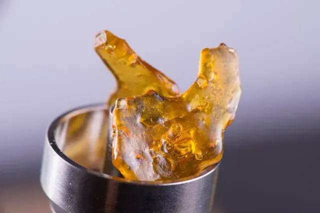 Amber cannabis shatter concentrate loaded inside a vape pen heating chamber - Flo Dispensary