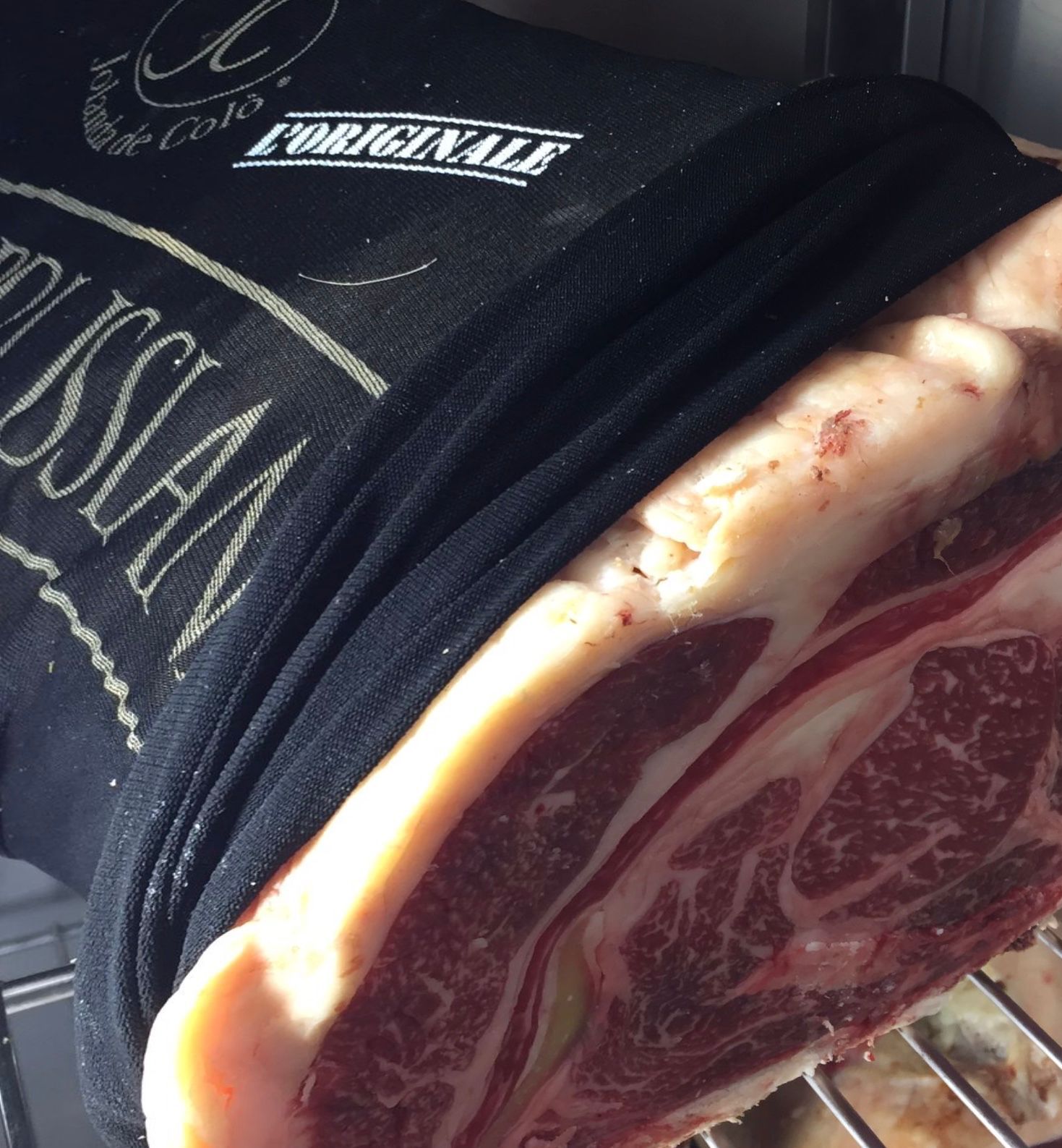 Primo piano di un grosso pezzo di carne cruda, parzialmente avvolto in una rete nera.