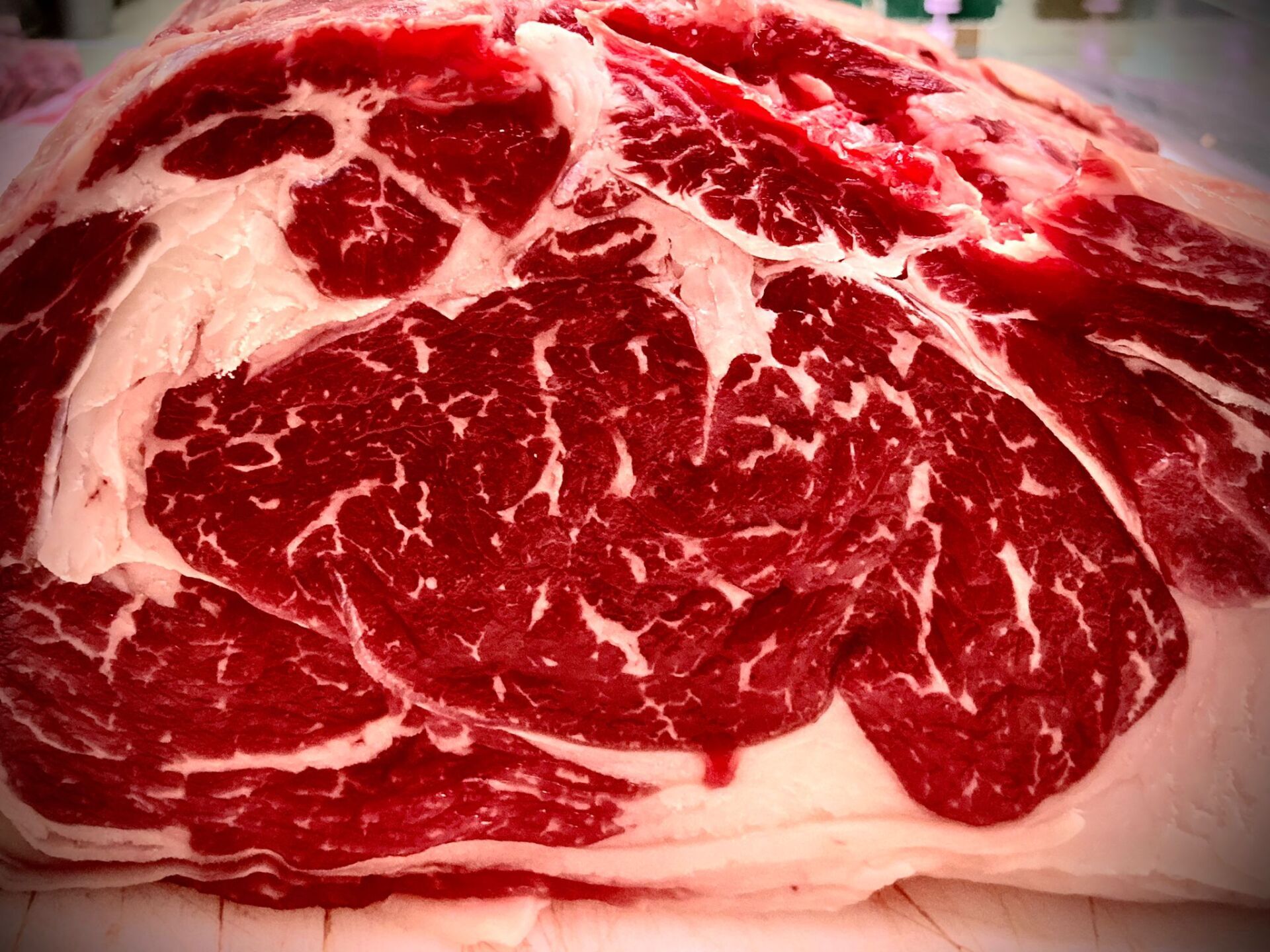 Primo piano di un grosso pezzo di manzo crudo con marezzature visibili e grasso circostante.