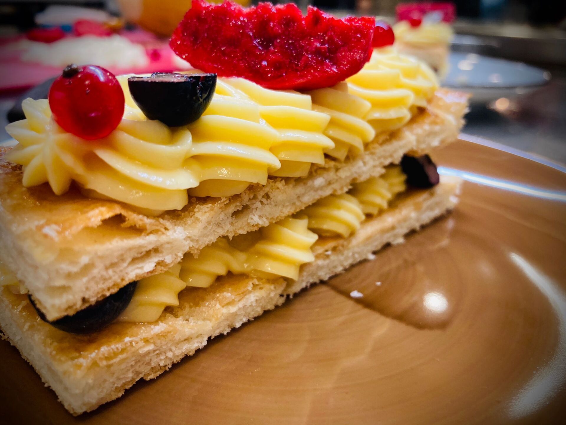 Dolce di pasta sfoglia a due strati con ripieno di crema, guarnito con frutti di bosco.