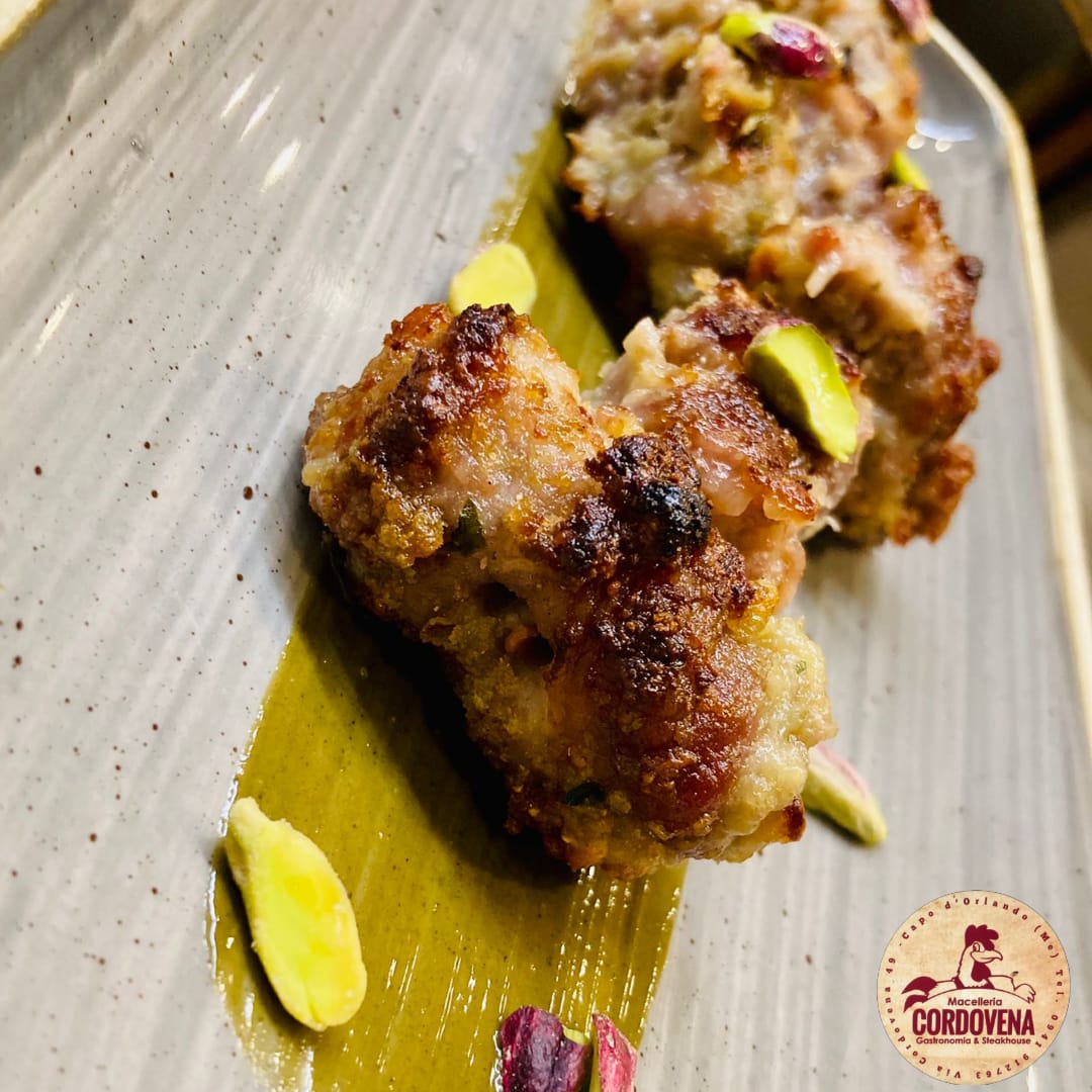 Polpette con pistacchi su un piatto con salsa verde.