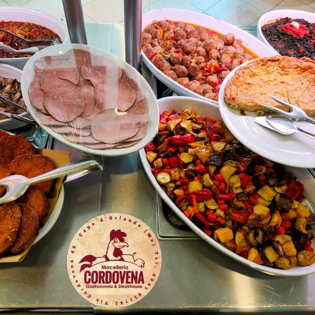 Esposizione di vari cibi cotti in piatti bianchi da portata a un buffet. È visibile il logo di Cordovena.
