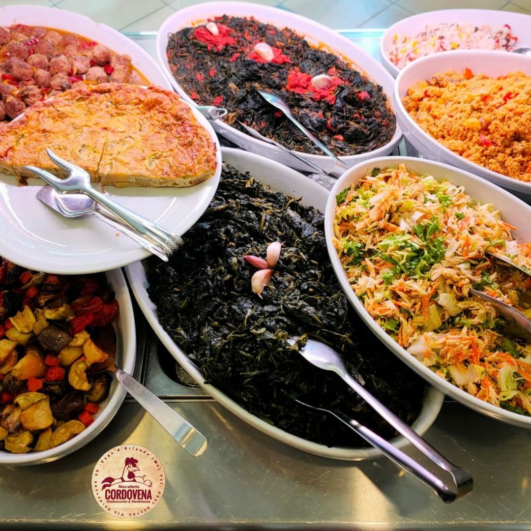 Buffet con vari piatti: verdure, cereali e un prodotto da forno, serviti in piatti ovali bianchi.