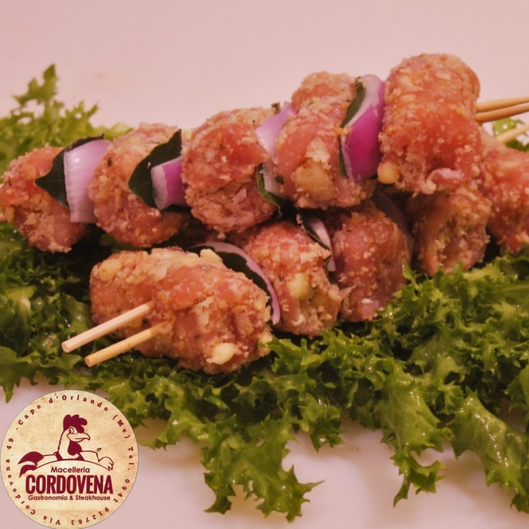 Spiedini di carne su lattuga, cipolla rossa ed erbe aromatiche.