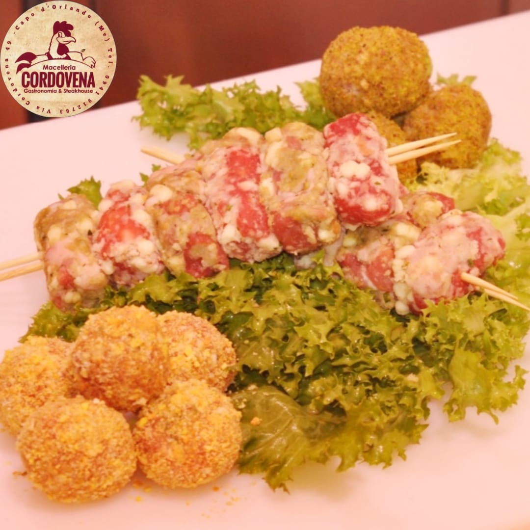 Spiedini di carne e polpette fritte su lattuga, con il logo Cordovena.