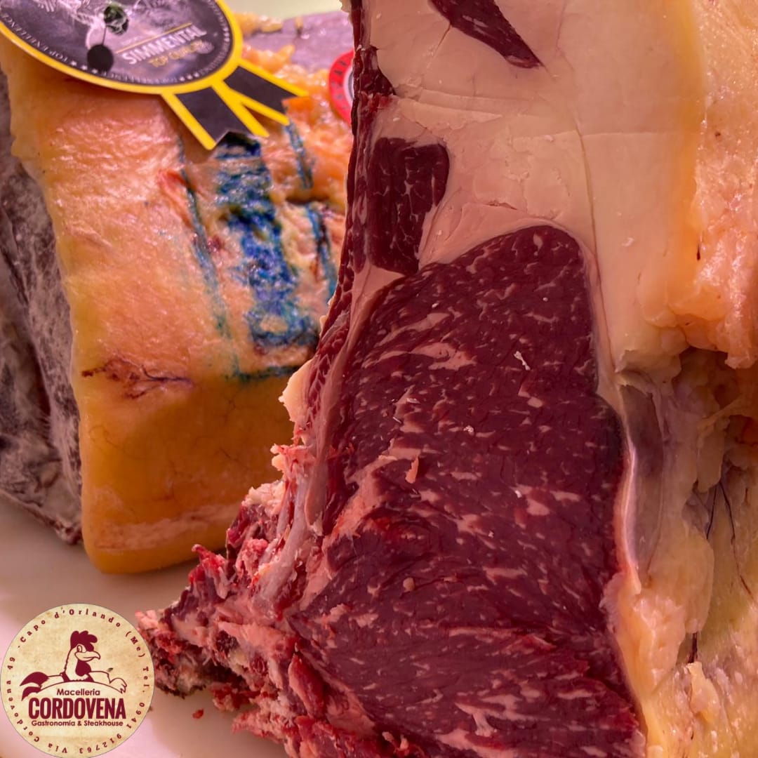 Primo piano di una grande bistecca cruda marmorizzata con uno spesso strato di grasso. Un adesivo è visibile sulla sinistra.