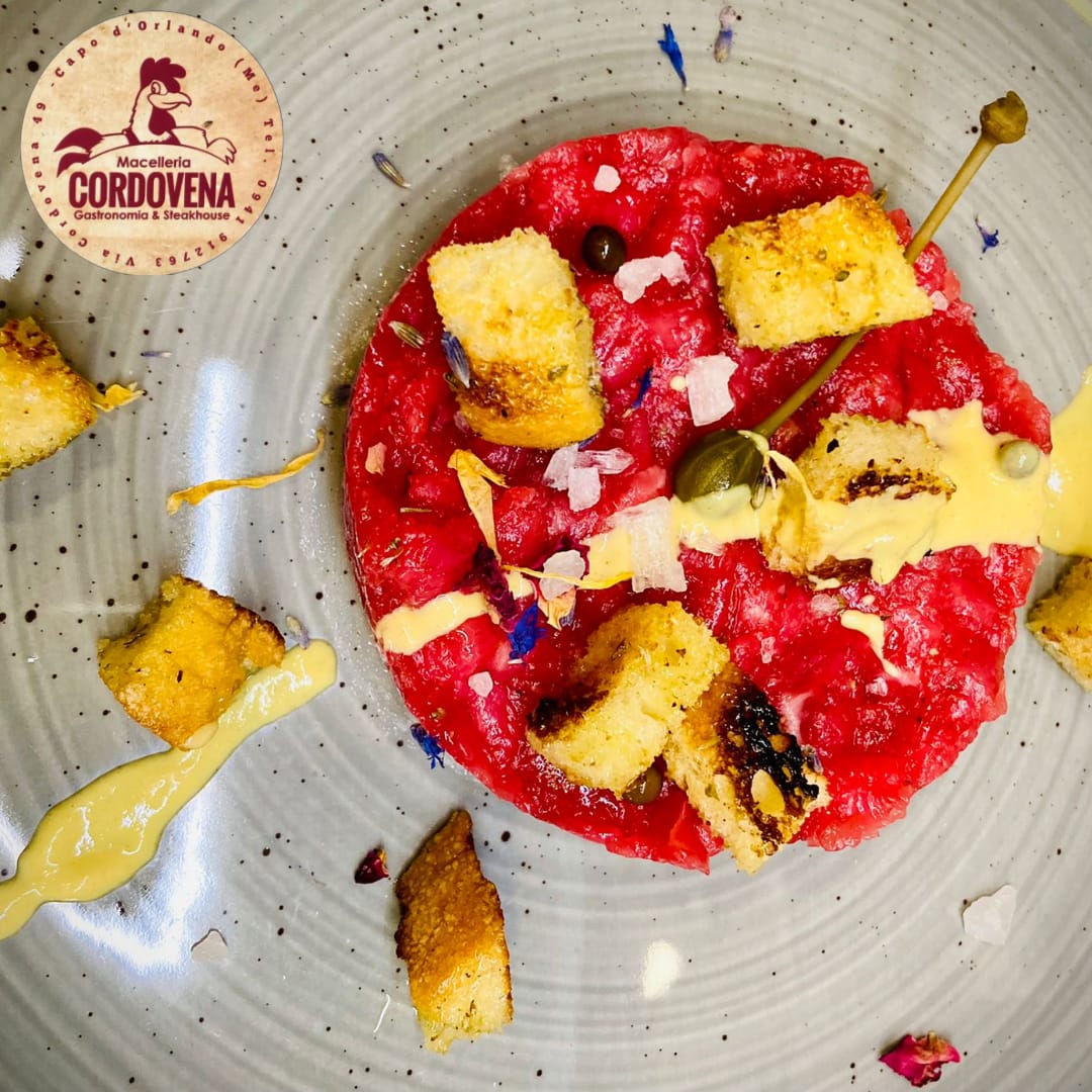Tartare di manzo cruda con crostini, capperi e salsa su un piatto grigio; logo Cordovena visibile.