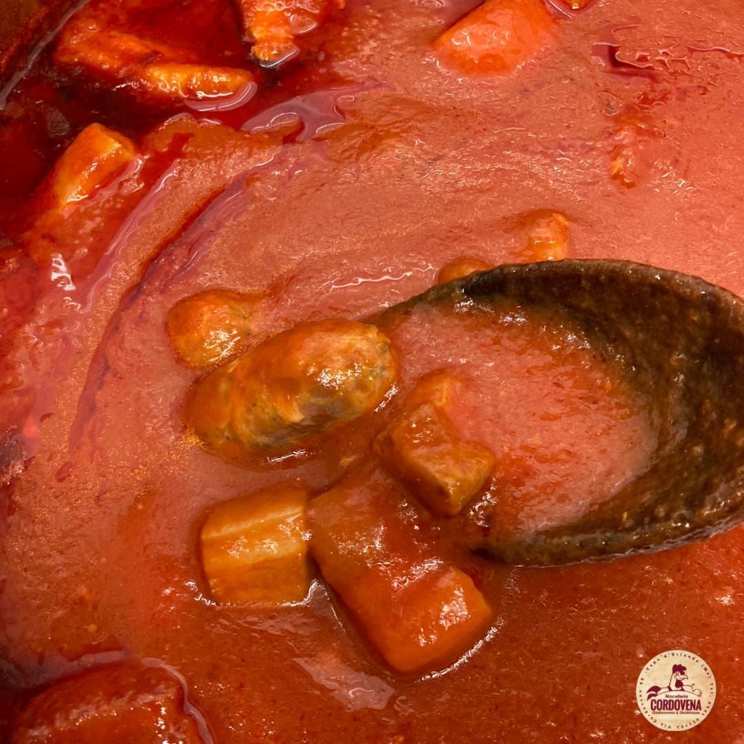Primo piano dello stufato di carote arancioni in salsa rossa, servito con un cucchiaio di legno.