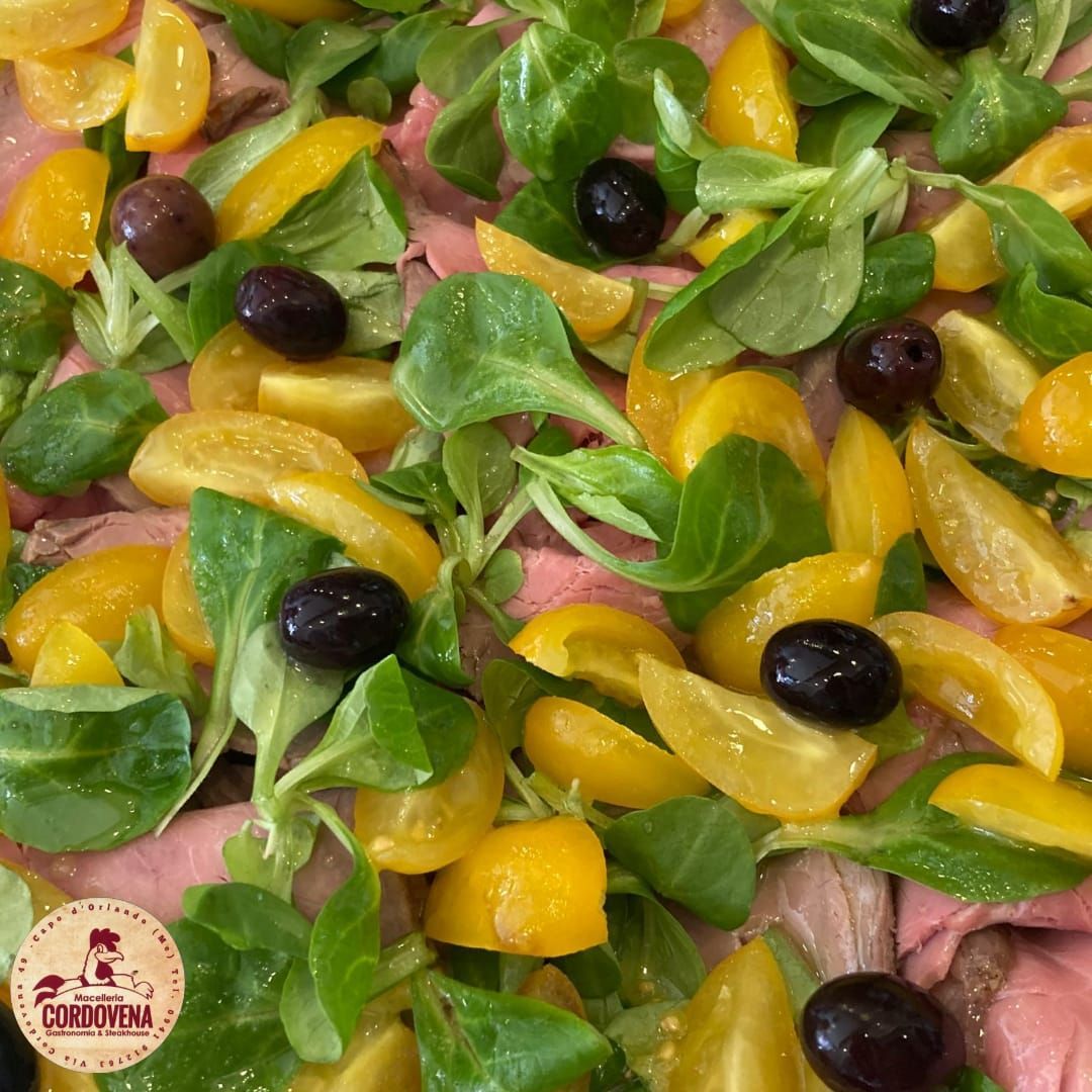 Insalata di roast beef con pomodori gialli, olive e verdure.