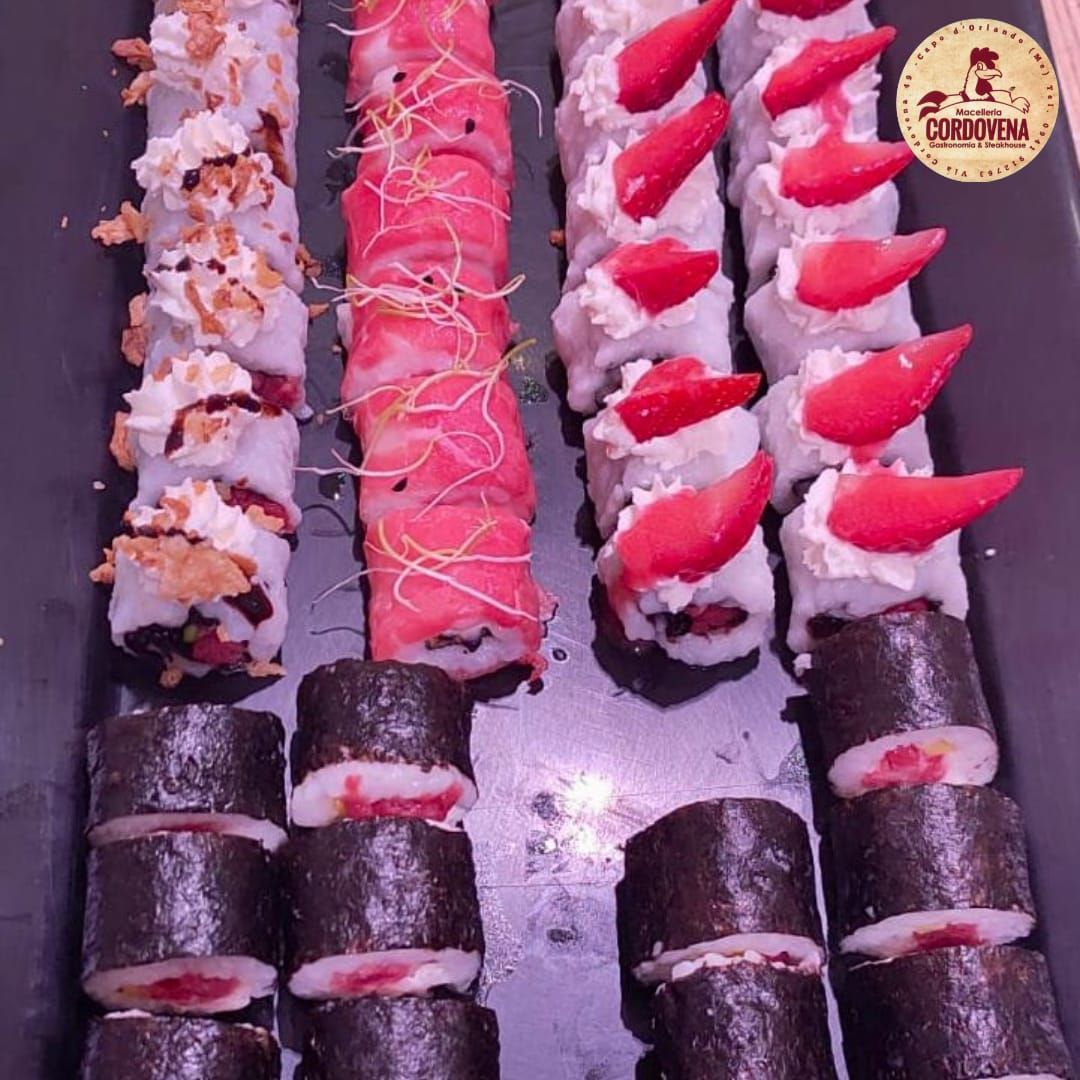 Piatto di sushi con vari involtini, tra cui involtini di alghe rosa, bianche e scure.