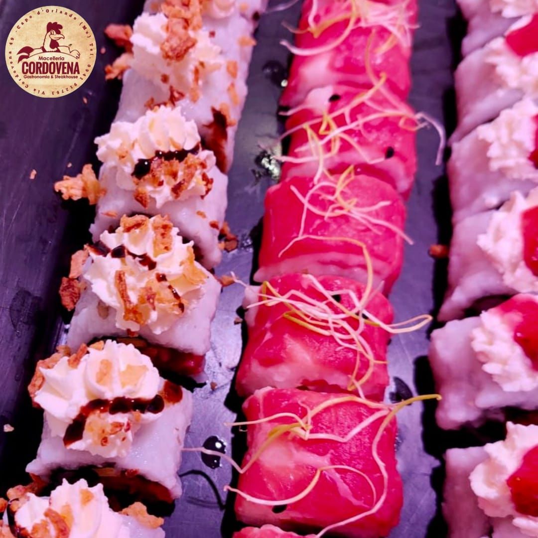 Rotoli di sushi, tre tipi disposti in file. I condimenti includono panna, pezzetti croccanti e dettagli rosa.