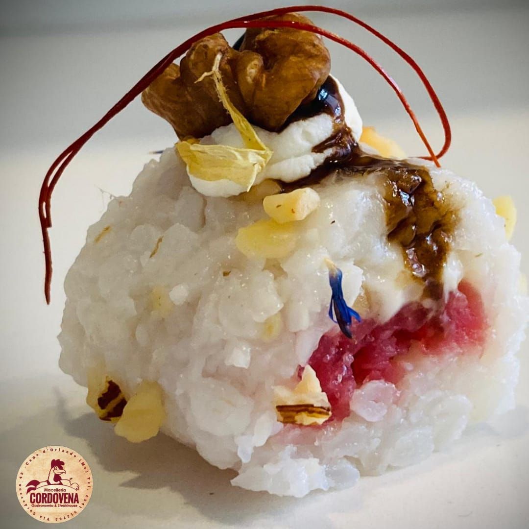 Pallina di riso bianco con guarnizione di noci, panna e salsa; guarnita con fili rossi.