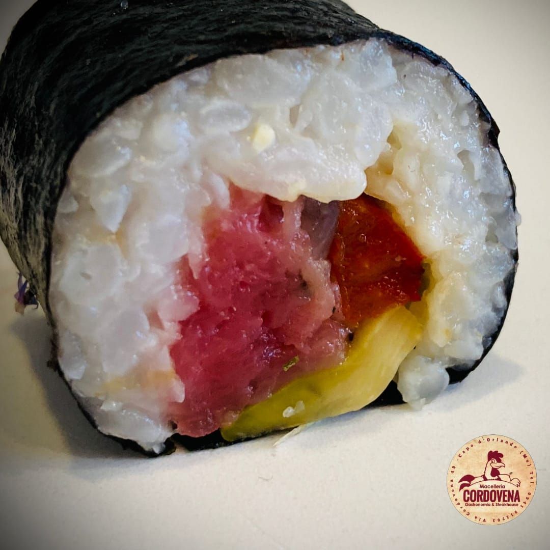 Primo piano di un rotolo di sushi con tonno, riso e alghe.
