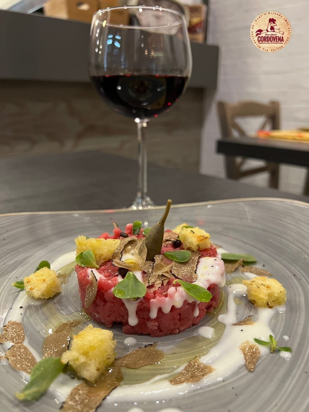 Piatto di tartare di manzo con tartufo e calice di vino.