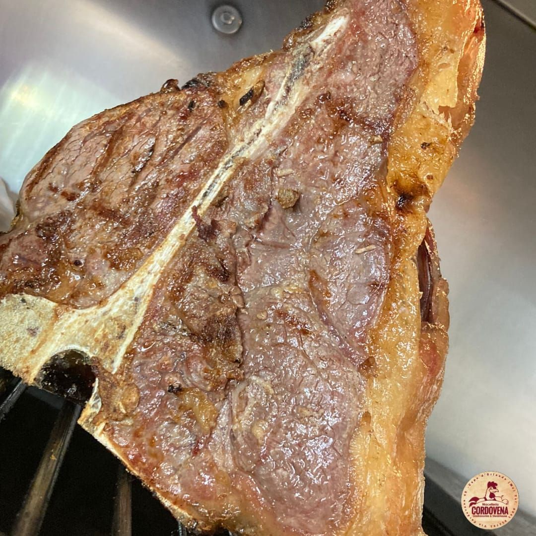 Bistecca alla fiorentina grigliata, al sangue, con i segni della griglia e l'osso visibili.