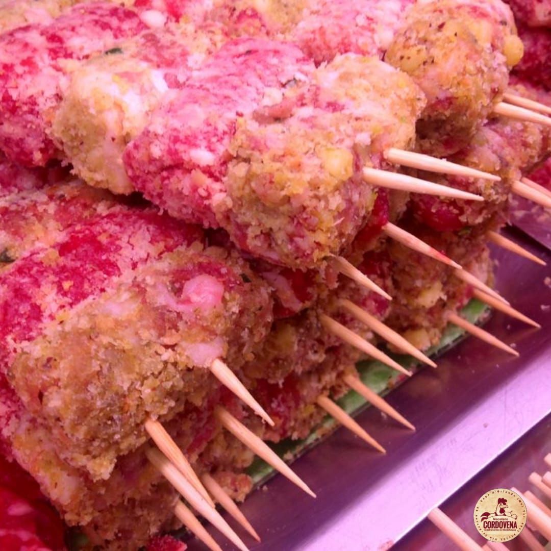 Polpette crude infilzate su spiedini, rosa e gialle, pronte per essere cotte.