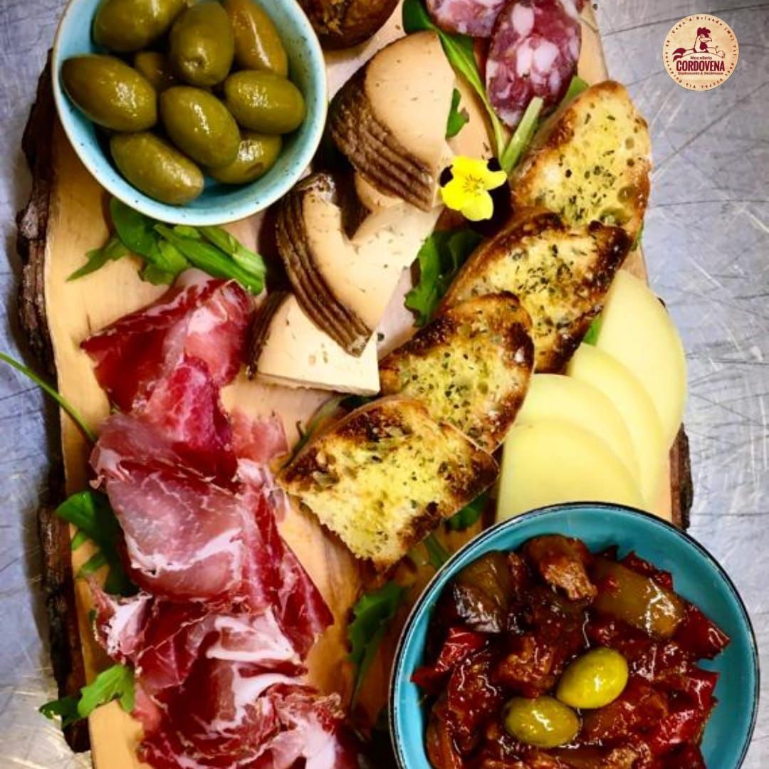 Tagliere di salumi con olive, salumi, formaggi e pane tostato.