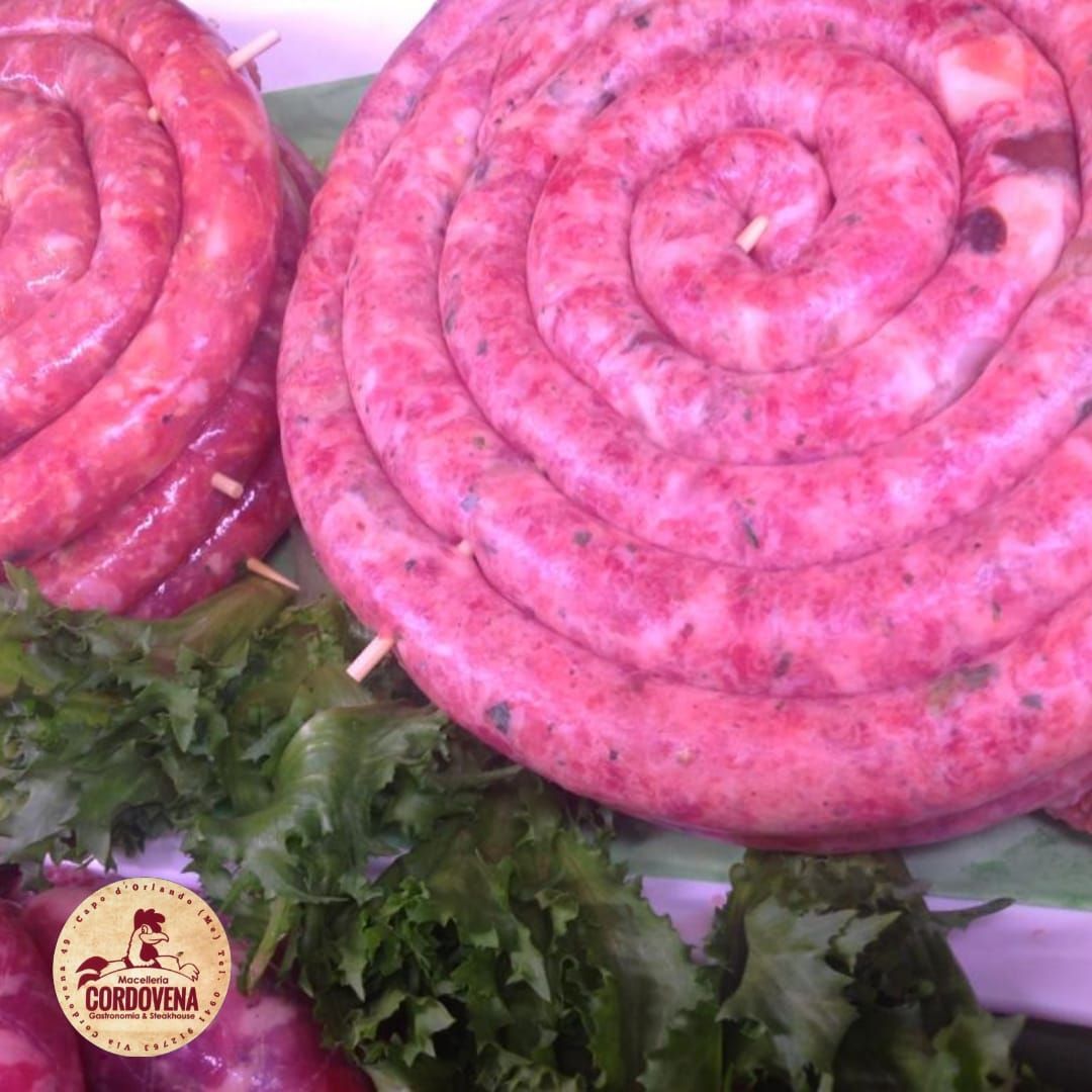 Salsiccia cruda arrotolata, rosa, con guarnizione verde.