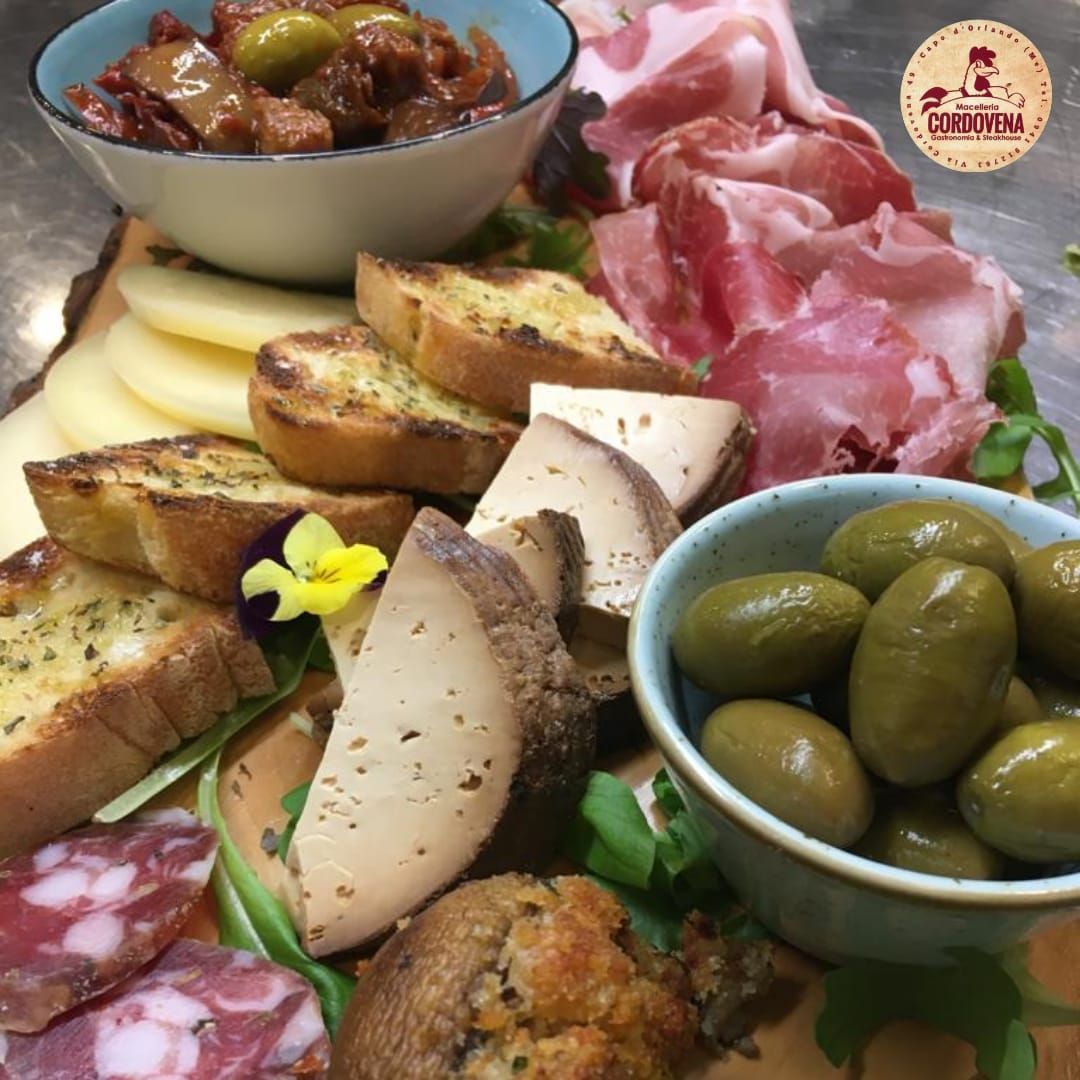 Tagliere di salumi con formaggi, carni, olive e pane tostato.