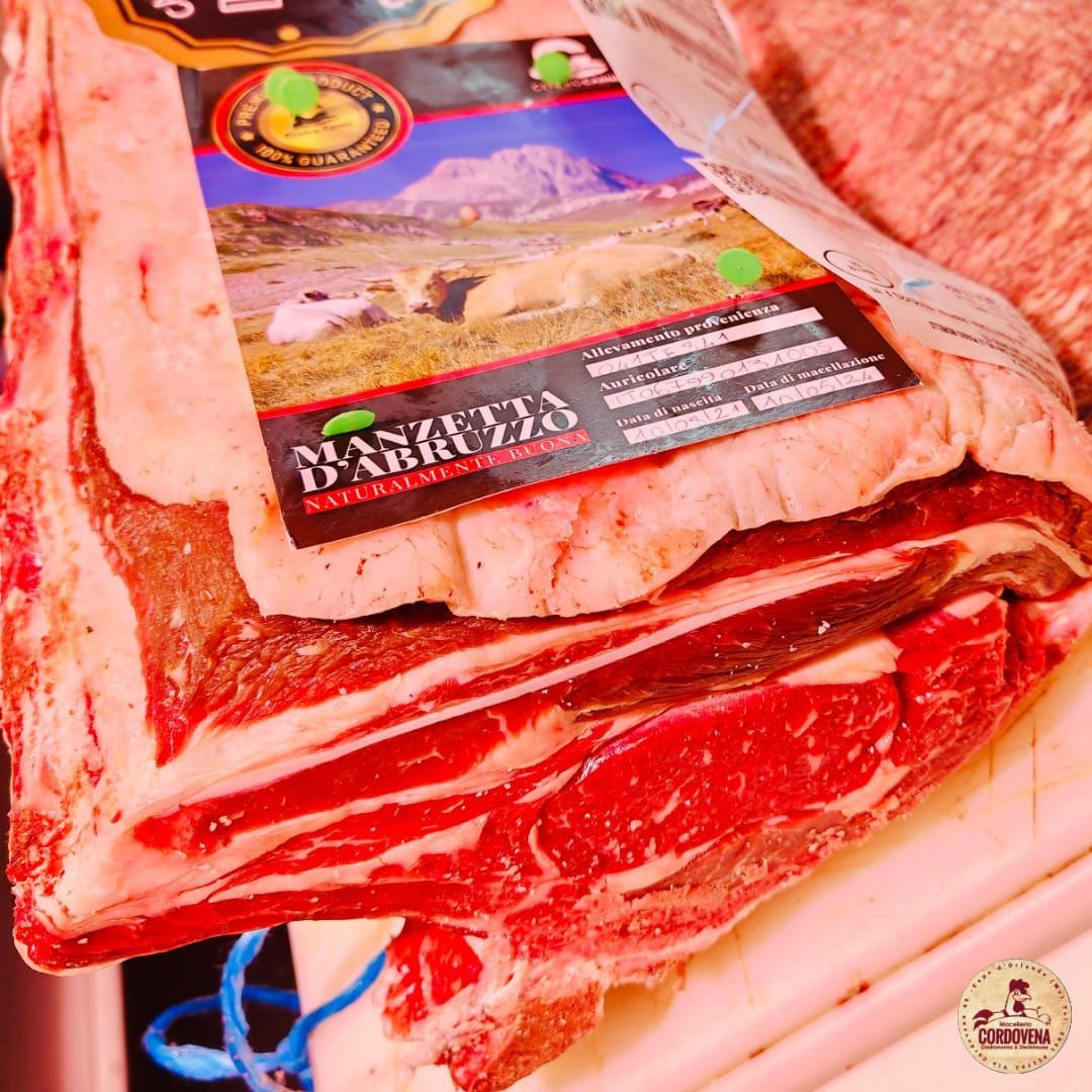 Primo piano di una pila di tagli di carne cruda con marezzatura visibile e un'etichetta con la scritta 