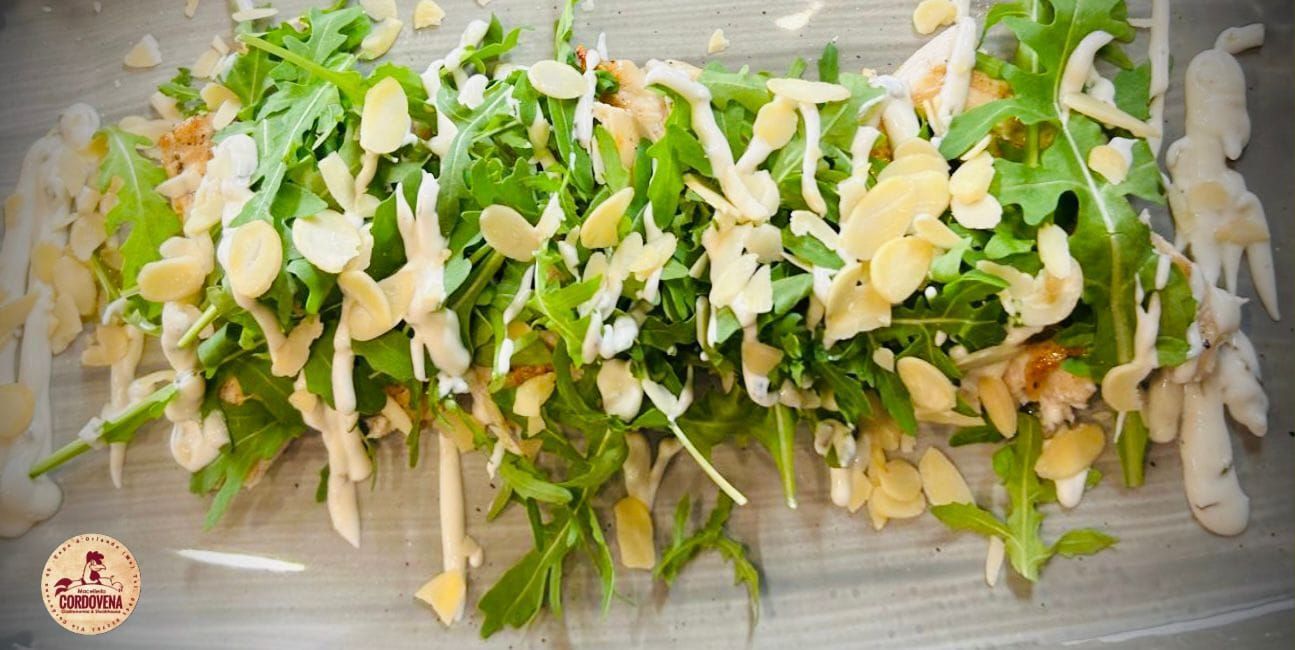 Insalata con rucola, mandorle a lamelle e condimento su una superficie leggera.