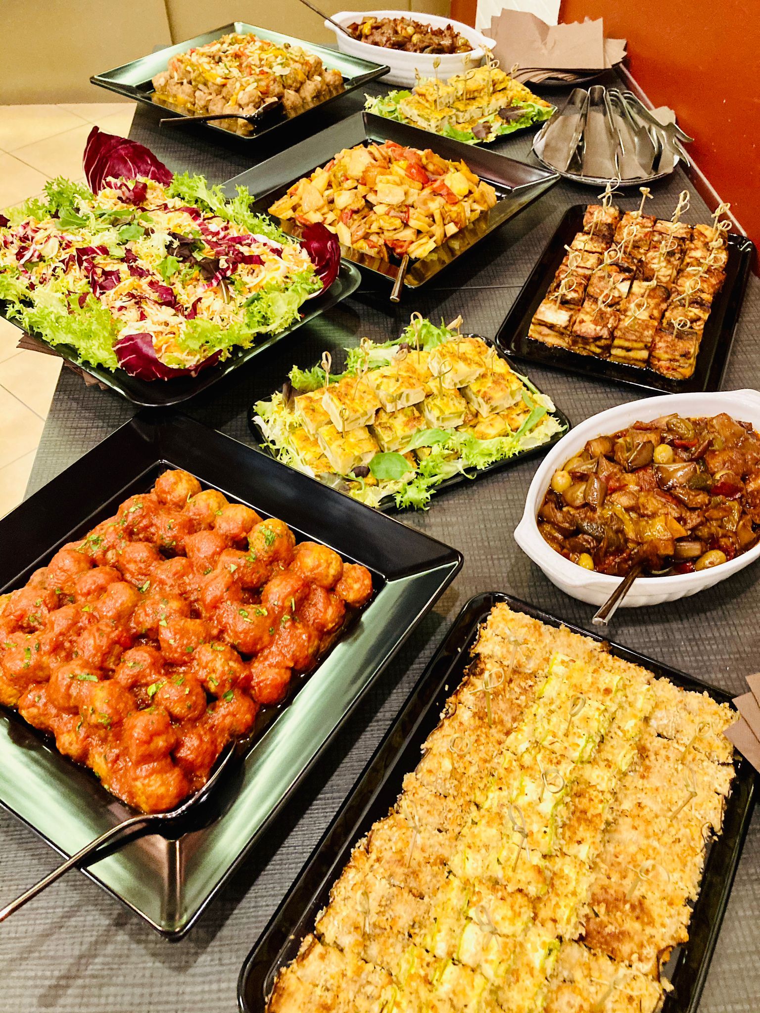 Tavolo buffet con vari piatti: insalate, fritture e stufati.