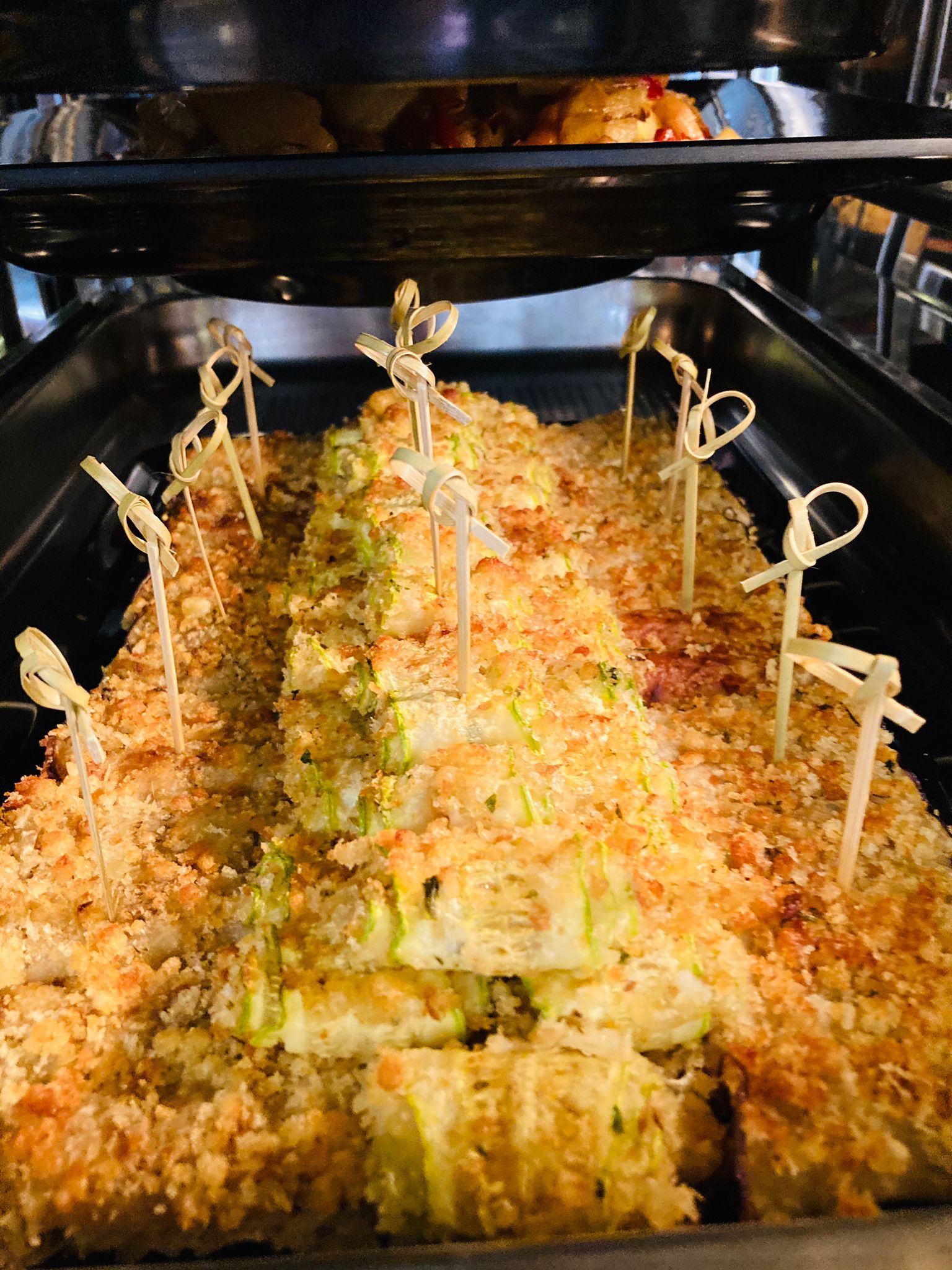 Antipasto di zucchine al forno con pangrattato, infilzate con stuzzicadenti decorativi.