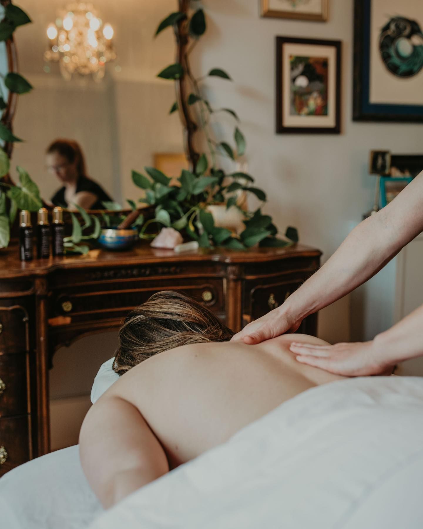 A woman is laying on a massage table getting a massage from another woman.
