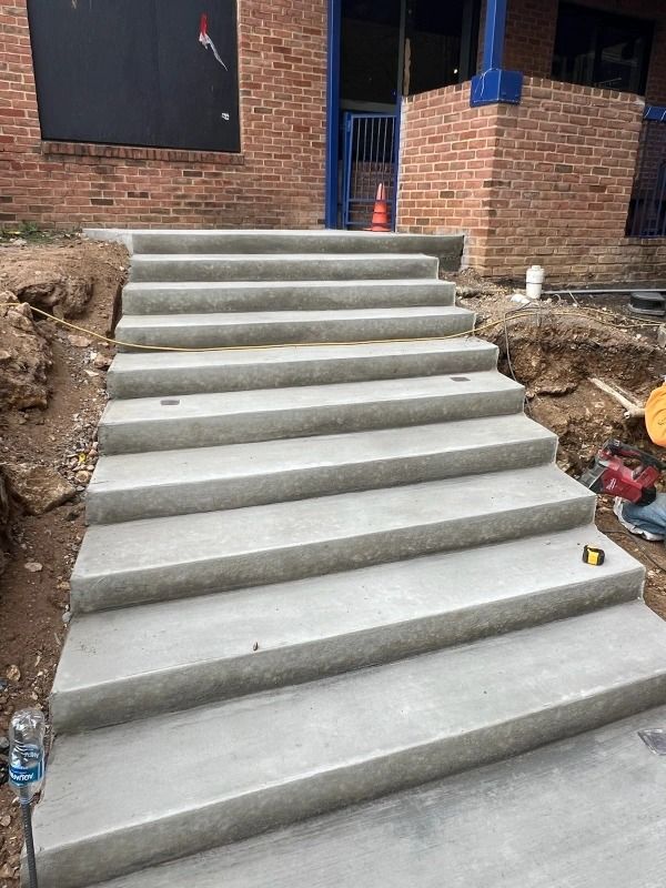 Concrete stairs leading up to a brick building, construction site setting.