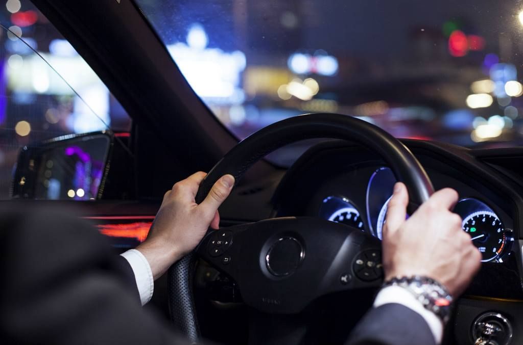 A man in a suit is driving a car at night.