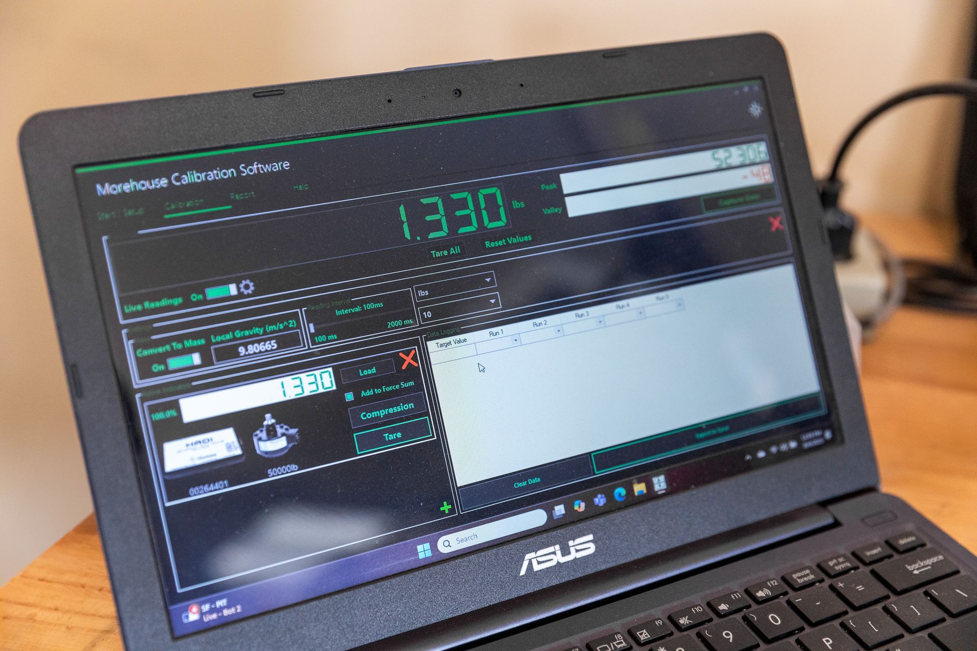 Black ASUS laptop displays a green and white software interface. The screen shows a large number
